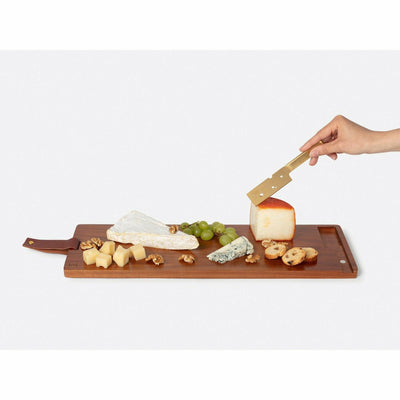 hand cutting cheese on wooden cheese board