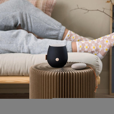 woman listening to black kreafunk aJazz Qi wireless bluetooth speaker on couch